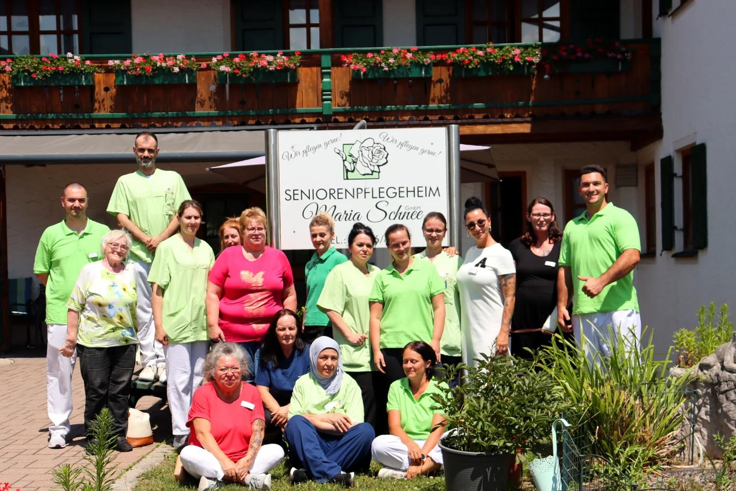 Teamfoto vor dem Schild des Seniorenpflegeheims Maria Schnee